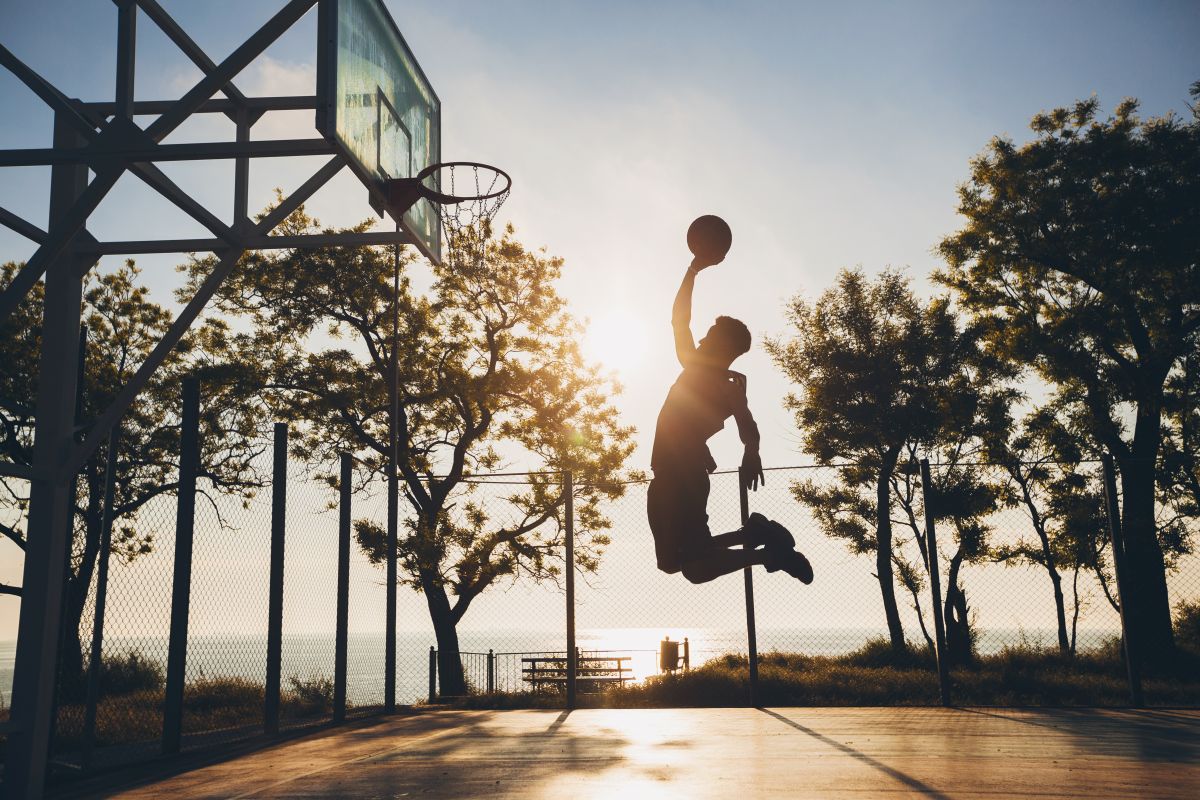 homem negro praticando esportes jogando basquete ao nascer do sol pulando silhueta