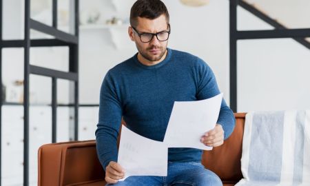 macho sentado no cauch e lendo documentos