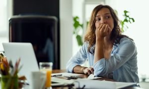 jovem preocupada pensando em algo enquanto calcula seu orcamento domestico