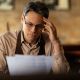 distraught small business owner reading reports while going through paperwork bar