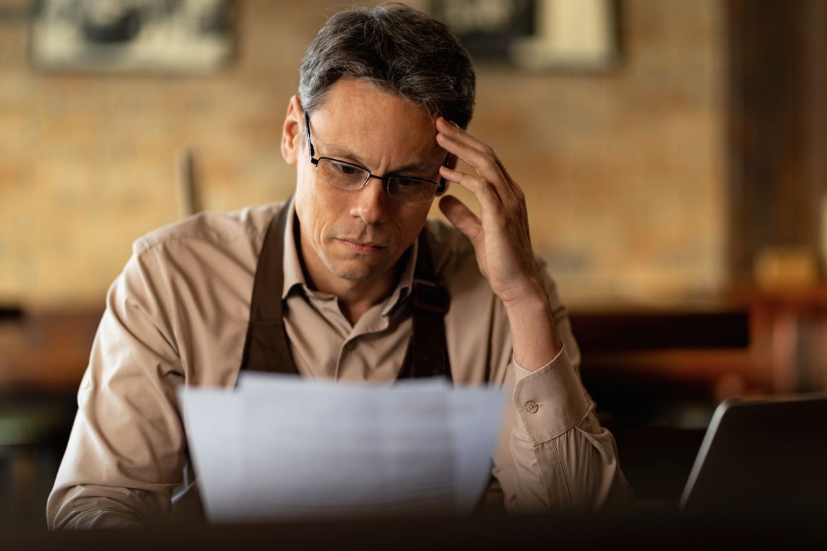 distraught small business owner reading reports while going through paperwork bar