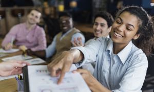 smiley woman showing graph office with coworkers