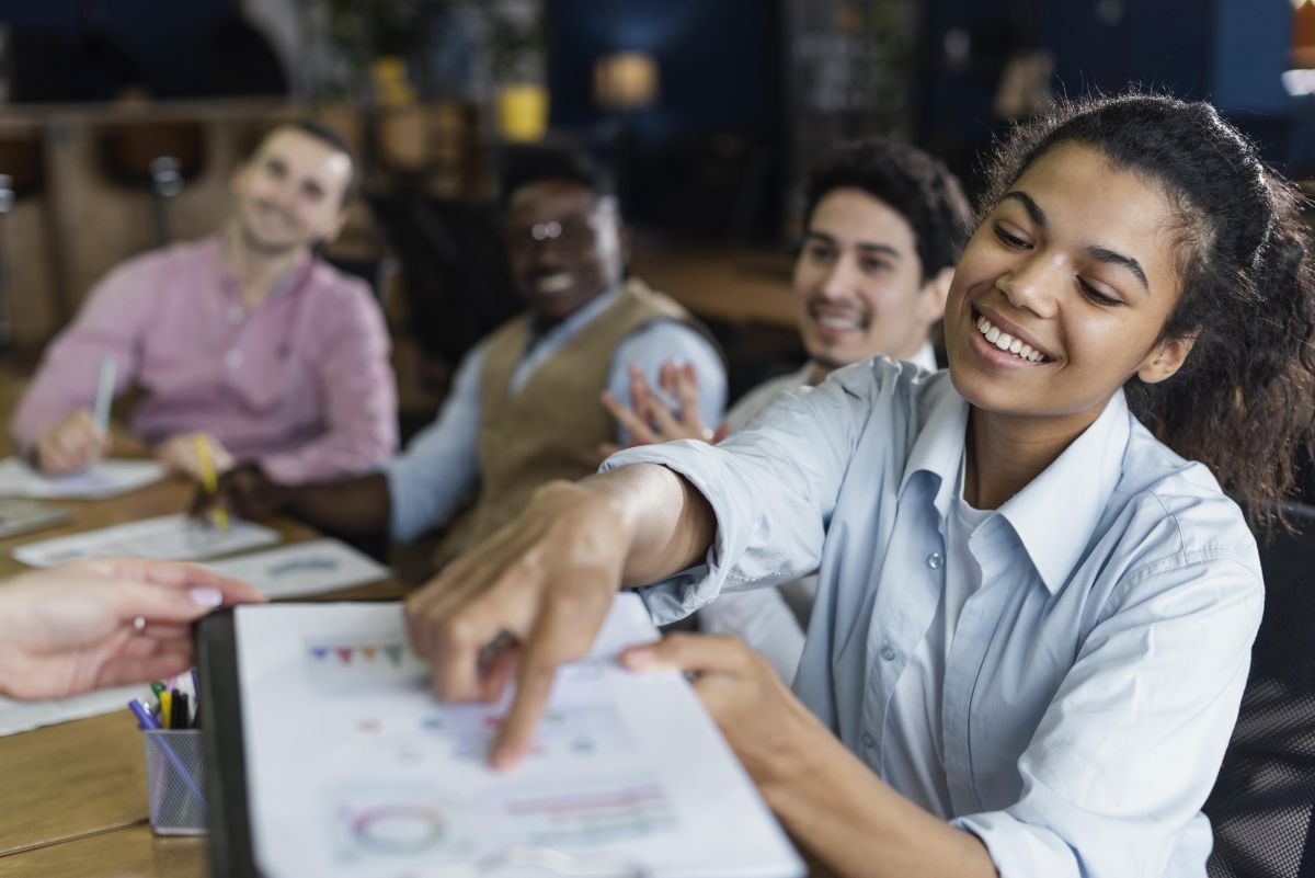 smiley woman showing graph office with coworkers