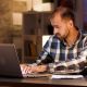businessman typing laptop searching through documents while working from home office