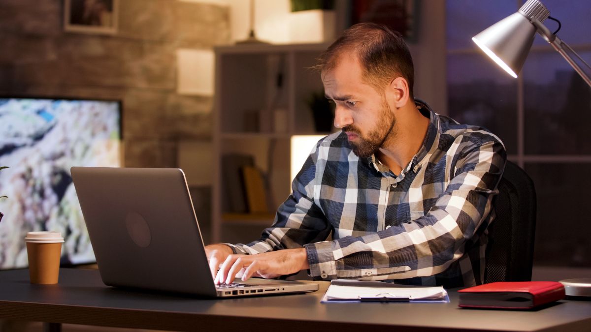 businessman typing laptop searching through documents while working from home office